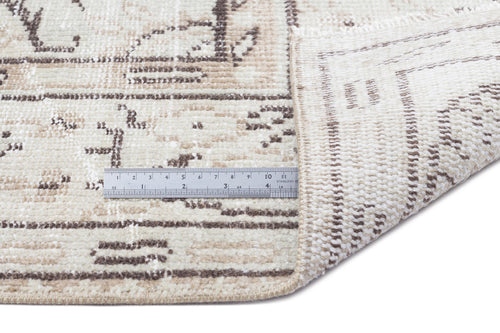 Load image 1 in gallery view. Beige and cream distressed rug with a faded geometric pattern, shown with a metal ruler for scale.
