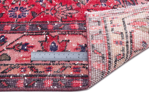 Load image 1 in gallery view. Distressed red and purple floral patterned rug with a folded corner revealing the beige backing and a metal ruler.