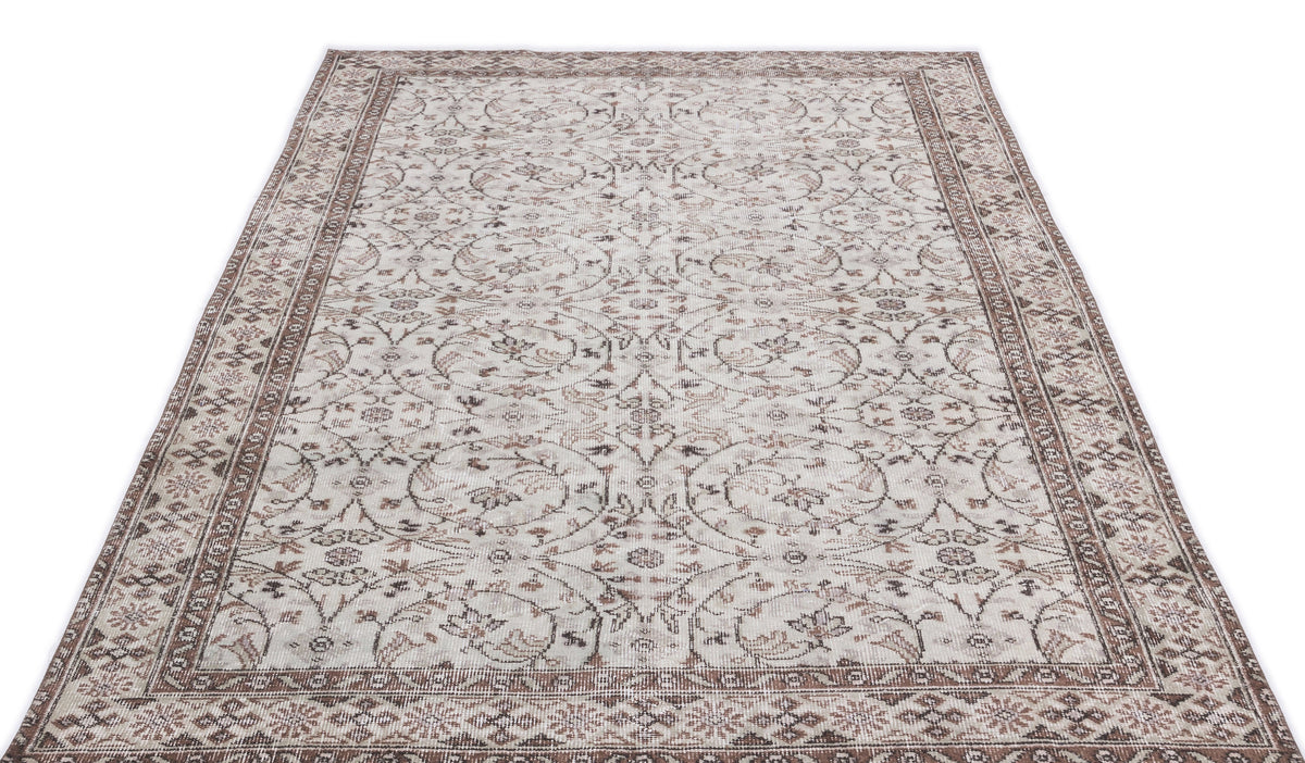 Beige and brown vintage-style rug with a distressed floral vine pattern and a decorative border.