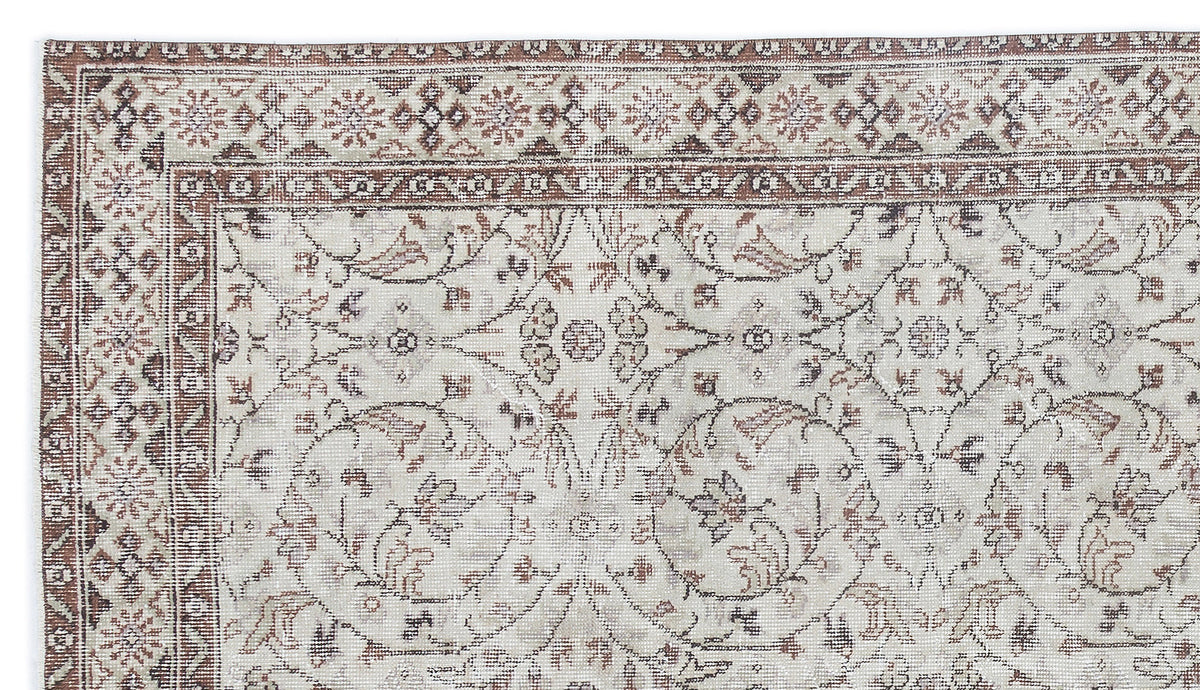 Beige and brown traditional rug with a distressed floral medallion pattern and a detailed geometric border.