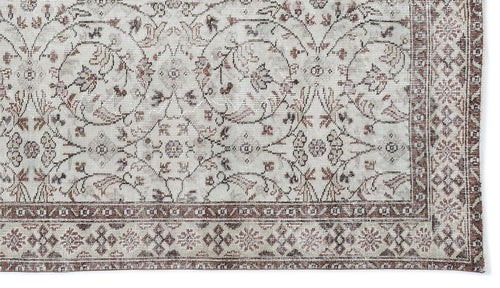 Load image 1 in gallery view. Distressed cream and brown rug with a traditional floral medallion pattern and a geometric border.