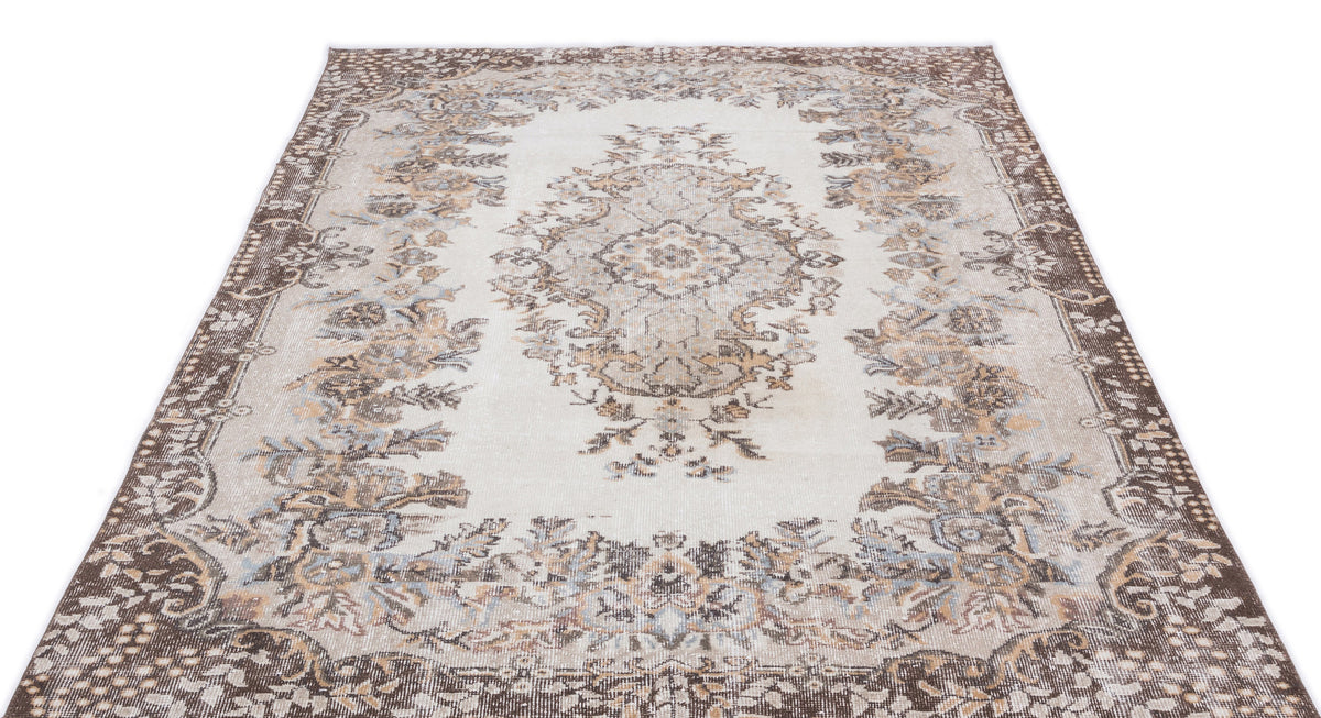 Cream and brown traditional rug with a central floral medallion and distressed border pattern on a white background.