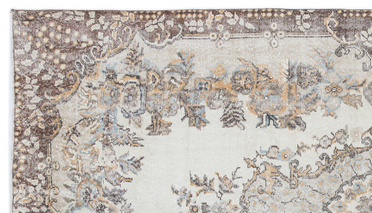 Distressed cream rug with brown and muted blue floral medallion patterns and a decorative border.