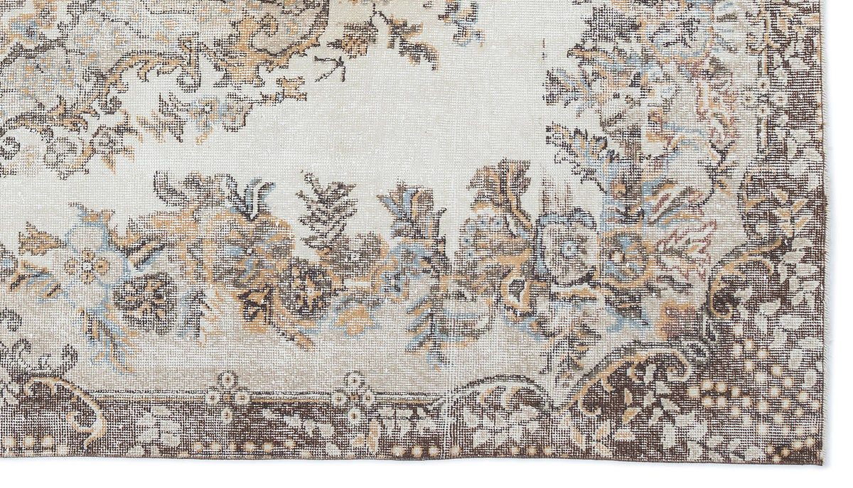 Cream, brown, and light blue distressed rug with a traditional floral medallion pattern and a dark border.