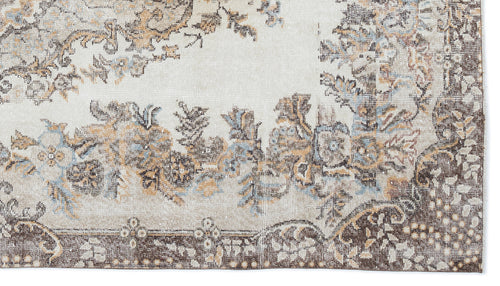 Load image 1 in gallery view. Cream, brown, and light blue distressed rug with a traditional floral medallion pattern and a dark border.