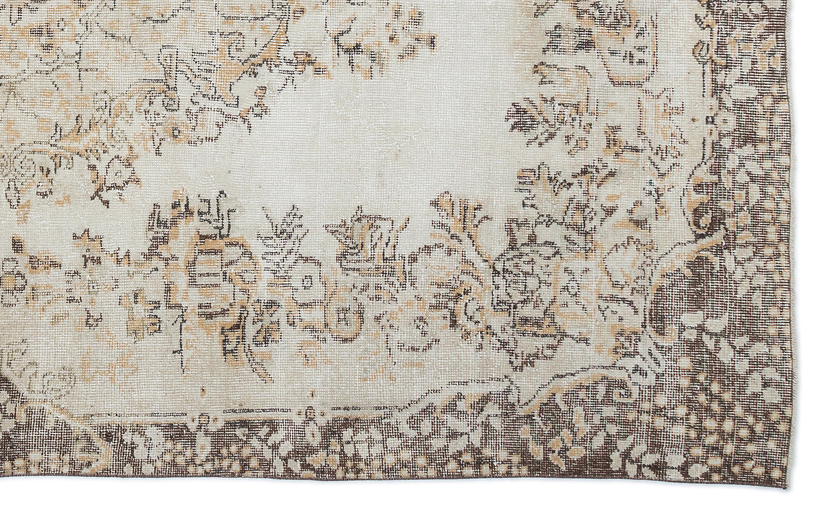 Cream and brown distressed rug with a faded floral medallion pattern and a wide, intricate border.
