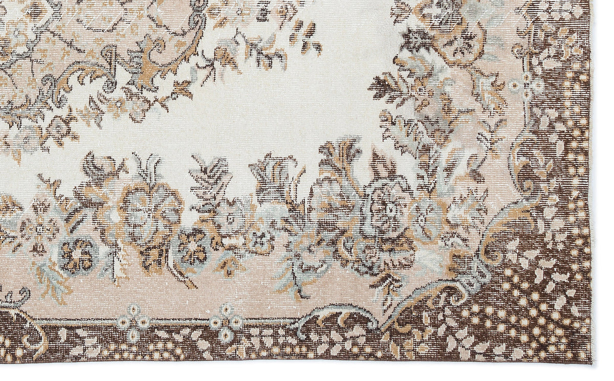 Cream, brown, and sage green rug with a distressed floral medallion pattern and a dark brown decorative border.