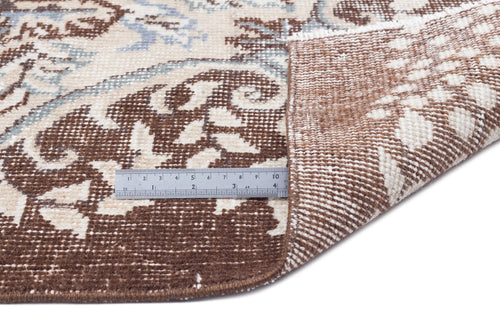 Load image 1 in gallery view. Brown, cream, and light blue floral medallion rug with a folded corner showing the woven backing and a metal ruler.