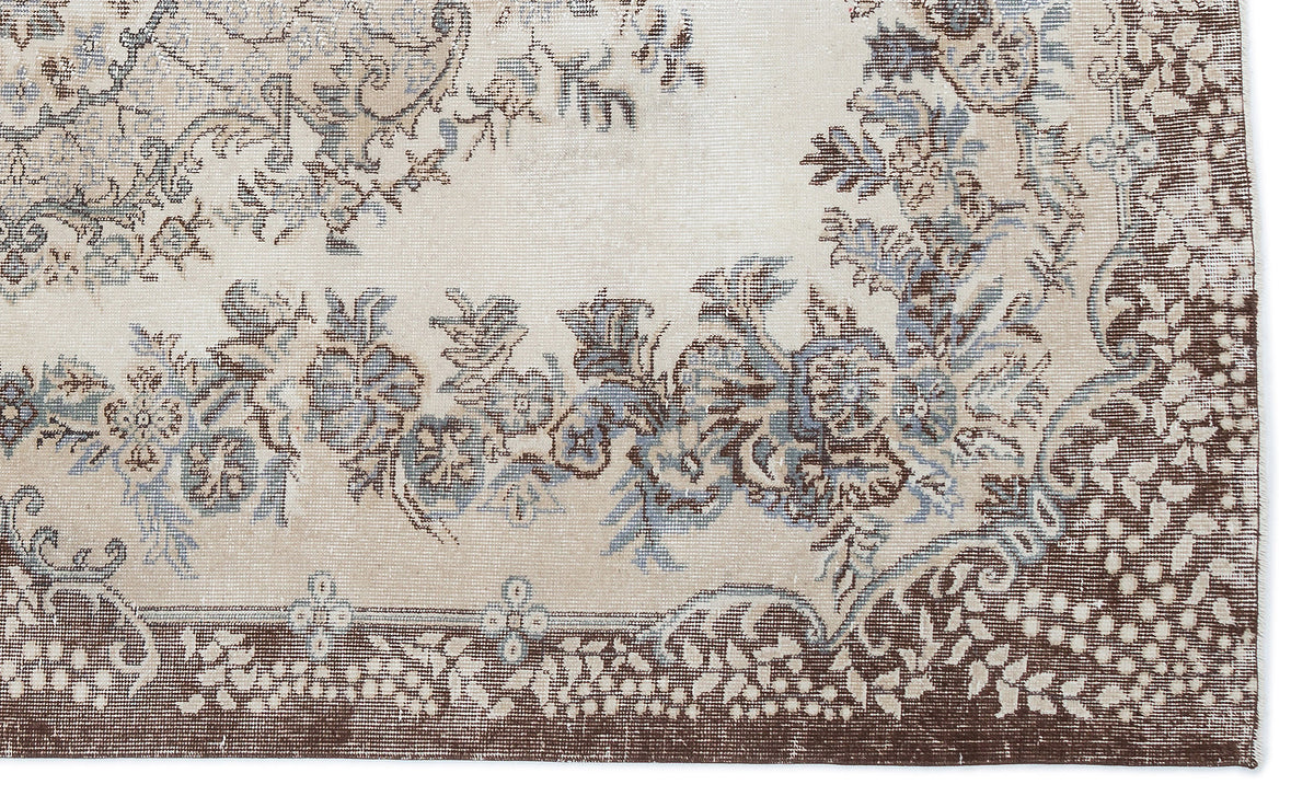 Beige rug with a distressed floral medallion pattern in shades of brown and slate blue.