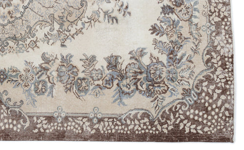 Load image 1 in gallery view. Beige rug with a distressed floral medallion pattern in shades of brown and slate blue.