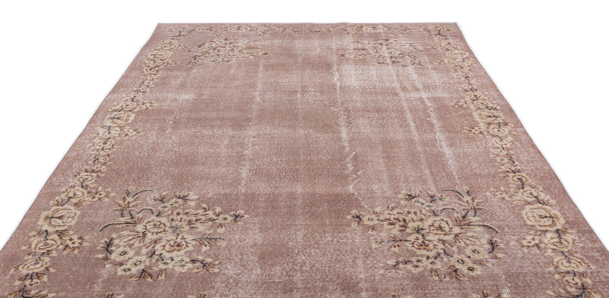 Dusty rose vintage-style rug with a distressed finish and a cream floral border on a white background.