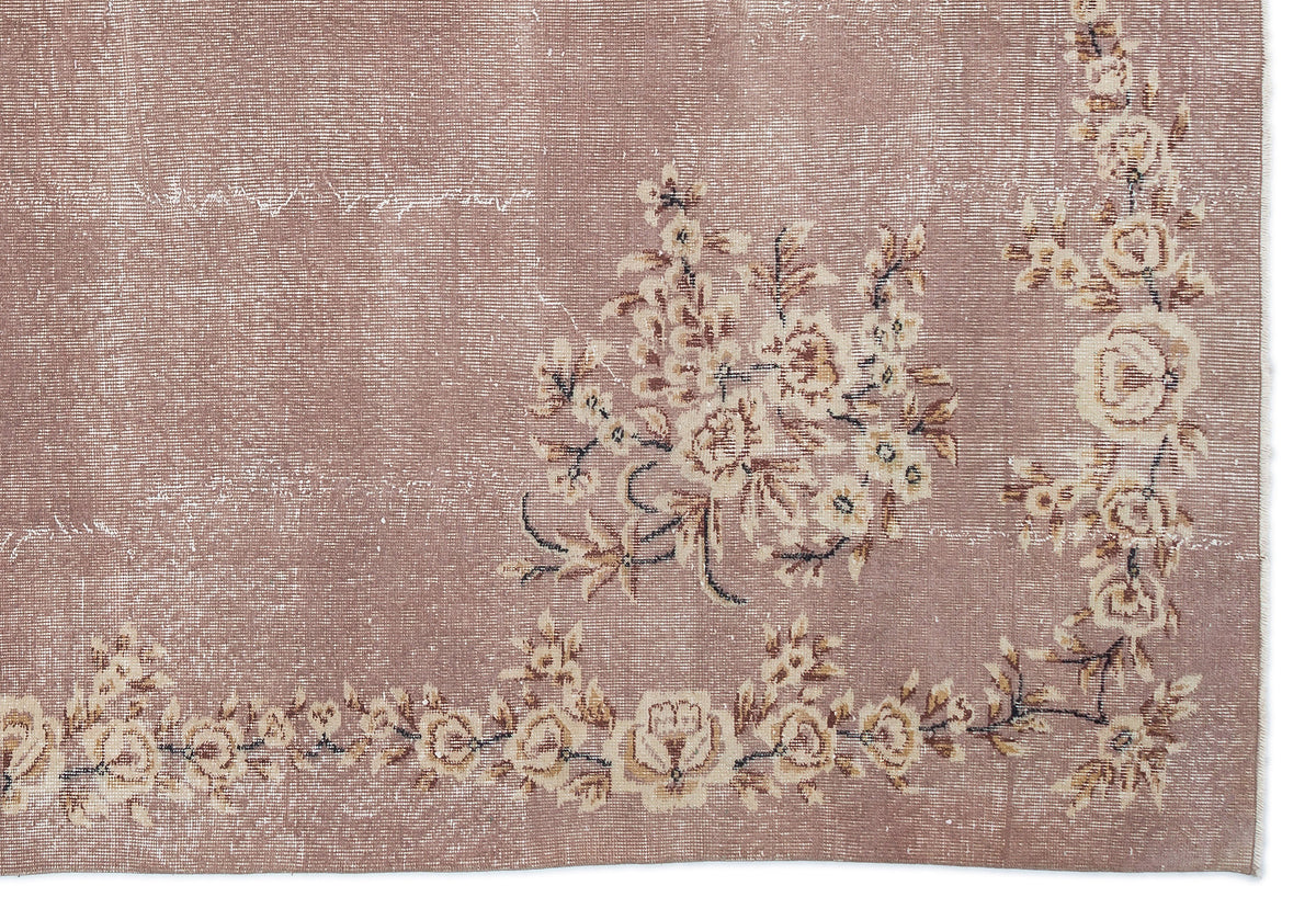 Dusty rose vintage-style rug with a distressed finish and cream floral border and central bouquet motif.