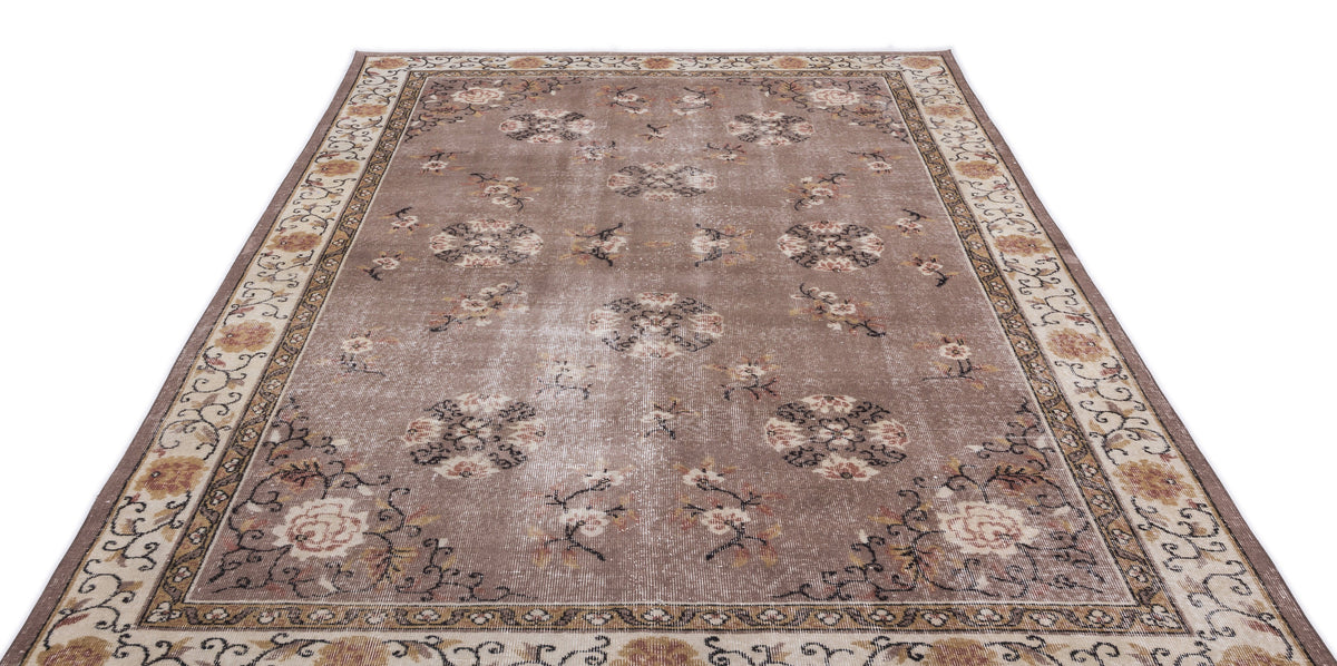 Taupe distressed area rug with a floral medallion pattern and a decorative border on a white background.