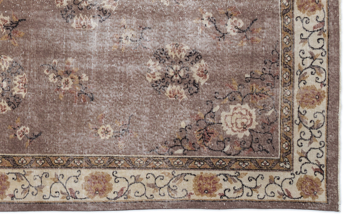 Taupe distressed rug with a faded floral medallion pattern and a decorative cream and brown border.