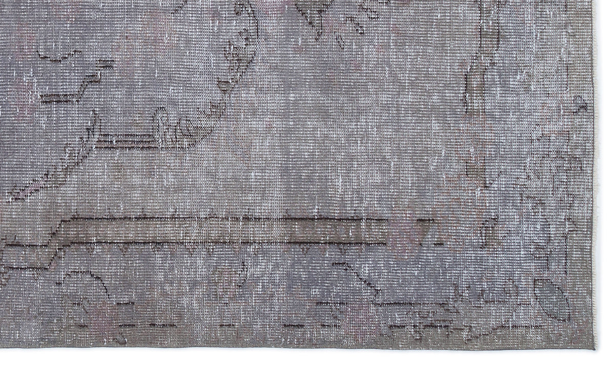 Grey and taupe distressed rug with a faded traditional medallion pattern and a visible fringe edge.