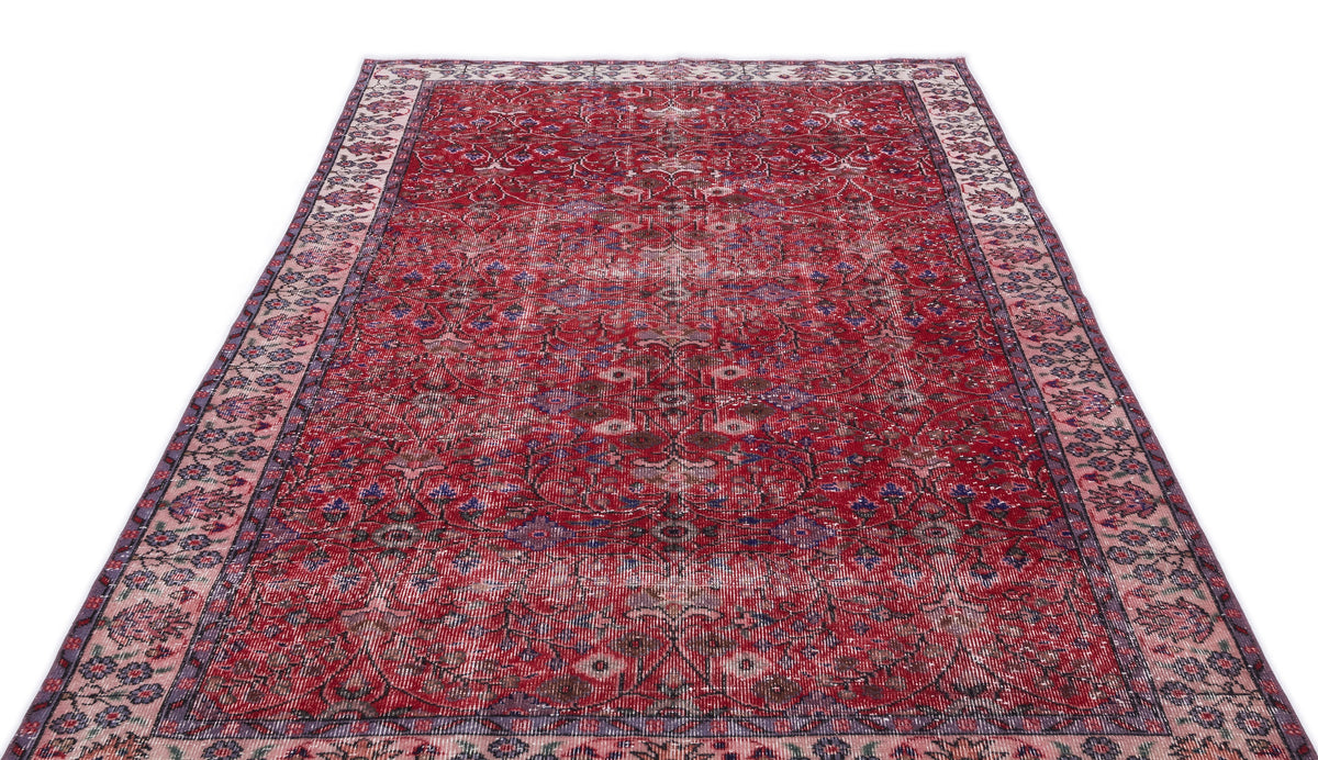 Distressed red Persian-style rug with a floral medallion pattern and a wide, intricate border on a white background.