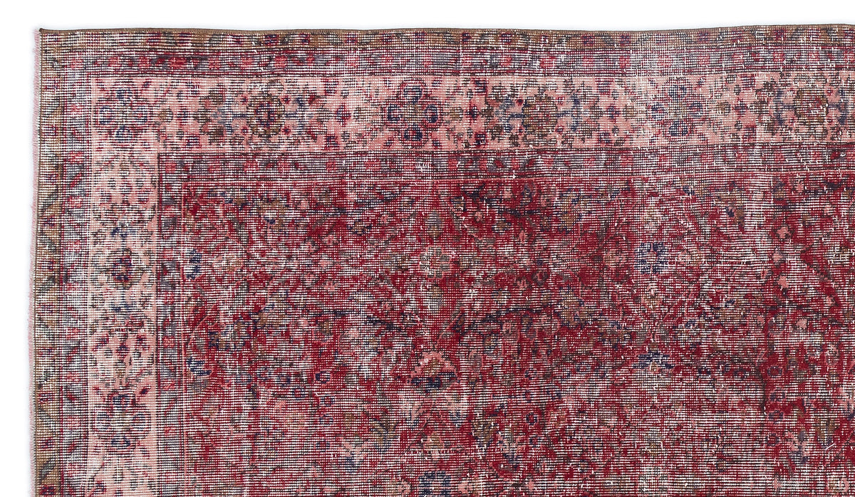 Distressed red and pink traditional rug with a faded floral border and intricate medallion pattern.