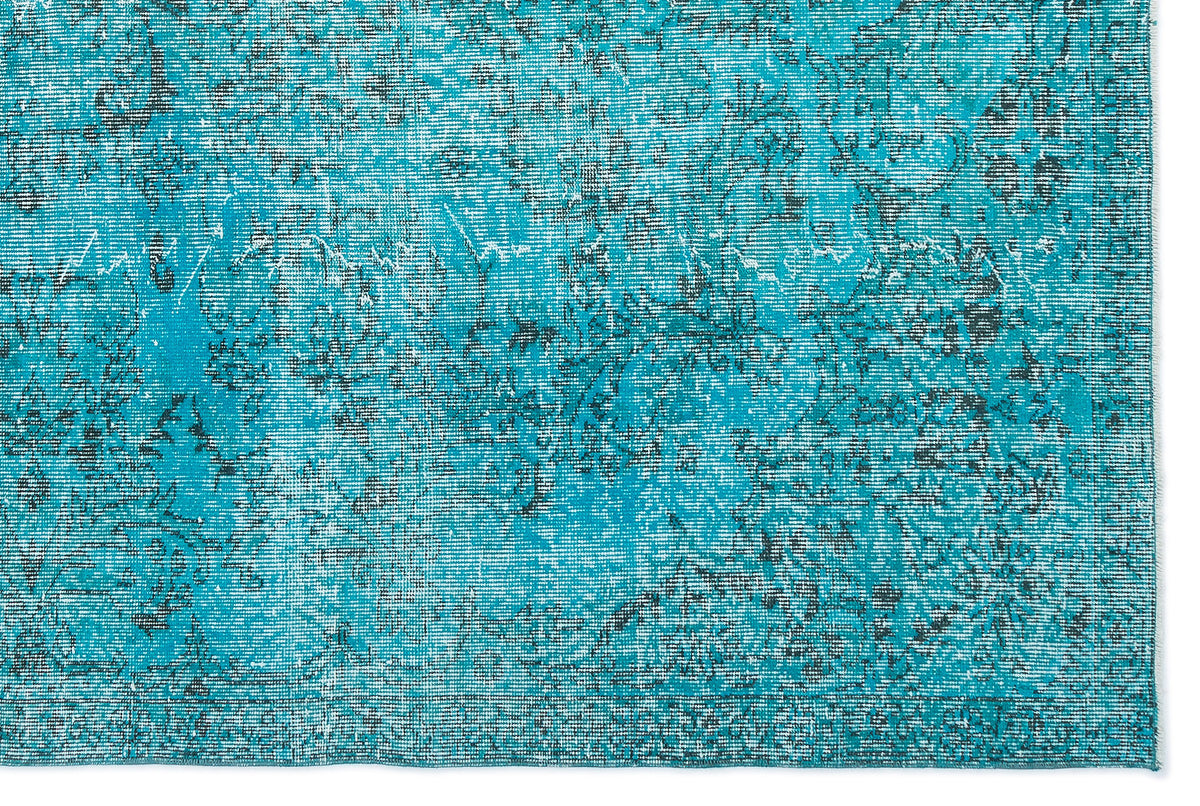 Turquoise and black distressed rug with a faded traditional floral pattern.