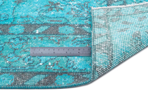 Load image 1 in gallery view. Turquoise and charcoal distressed medallion rug with a folded corner and a metal ruler for scale.
