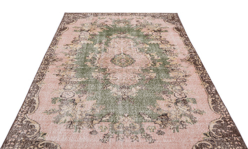 Load image 1 in gallery view. Distressed pink and green vintage-style rug with a central floral medallion and dark brown ornate border.