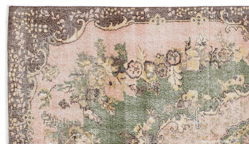 Load image 1 in gallery view. Distressed vintage-style rug with a pink field, dark brown border, and green and yellow floral medallion pattern.