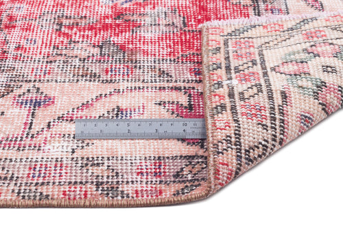 Load image 1 in gallery view. Distressed red and cream rug with a traditional floral medallion pattern, shown folded with a metal ruler for scale.
