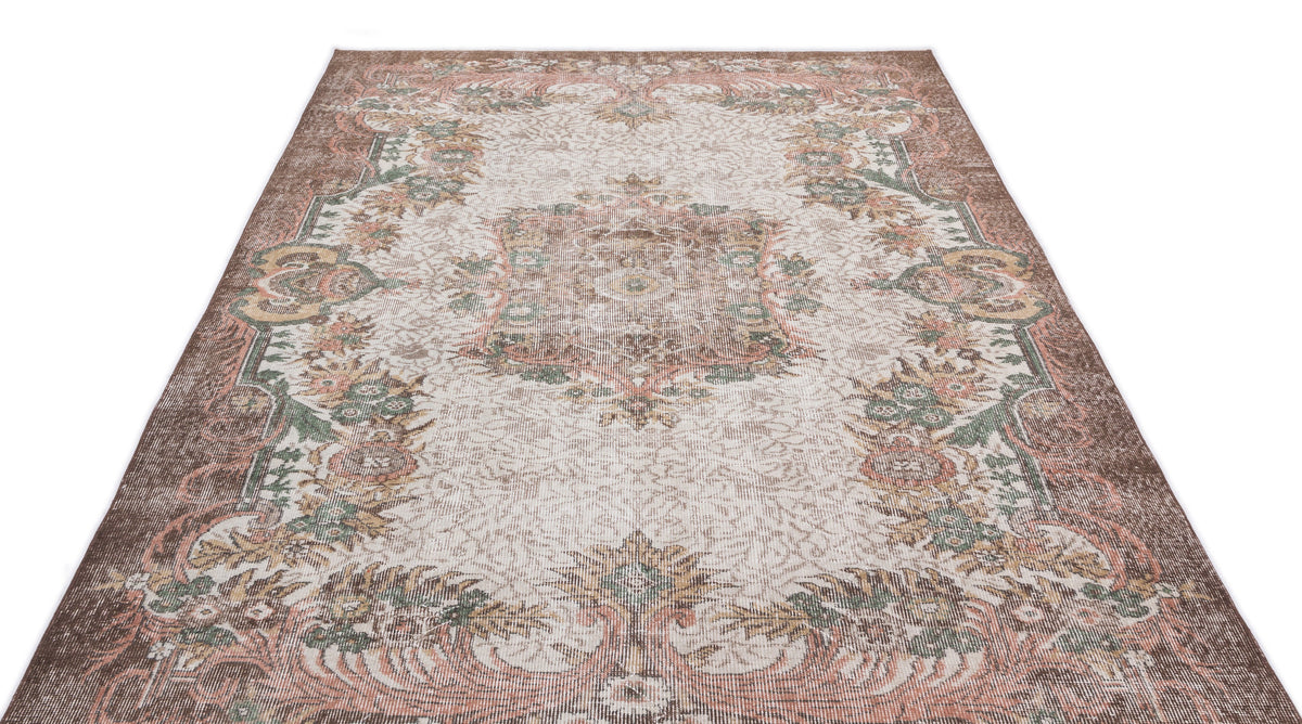 Distressed brown, cream, and sage green traditional rug with a central floral medallion and ornate border.