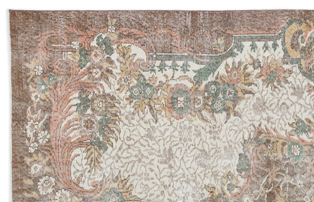 Distressed brown, cream, green, and terracotta rug with a traditional floral medallion pattern.