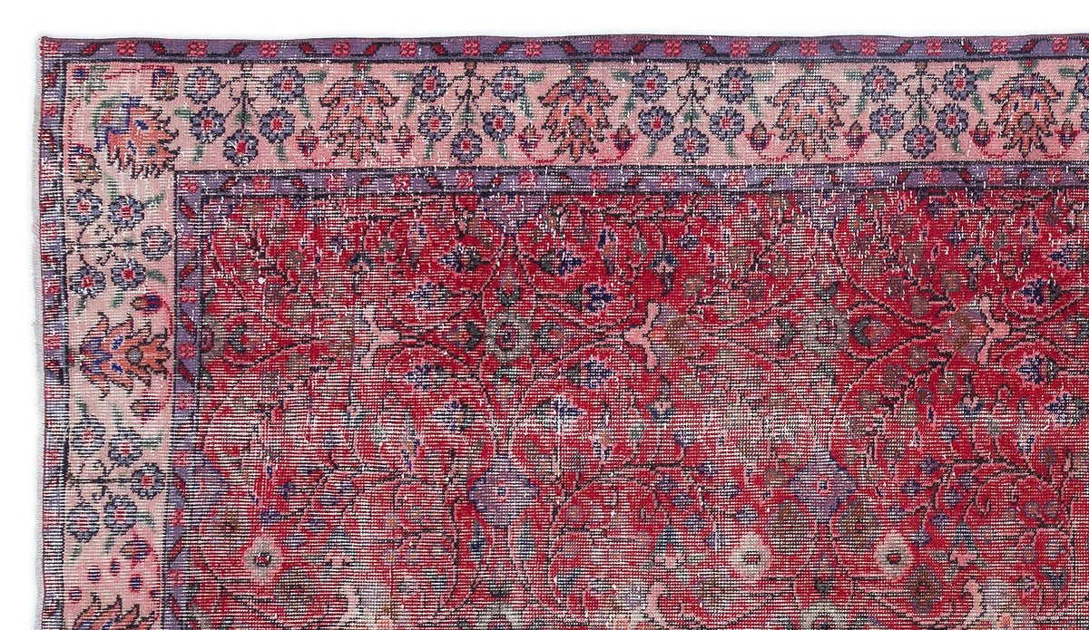 Distressed red rug with a floral medallion center and a pink and purple botanical border.