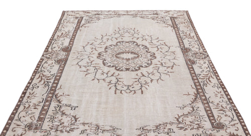 Load image 1 in gallery view. Beige and brown distressed rug with a central floral medallion and geometric border pattern on a white background.