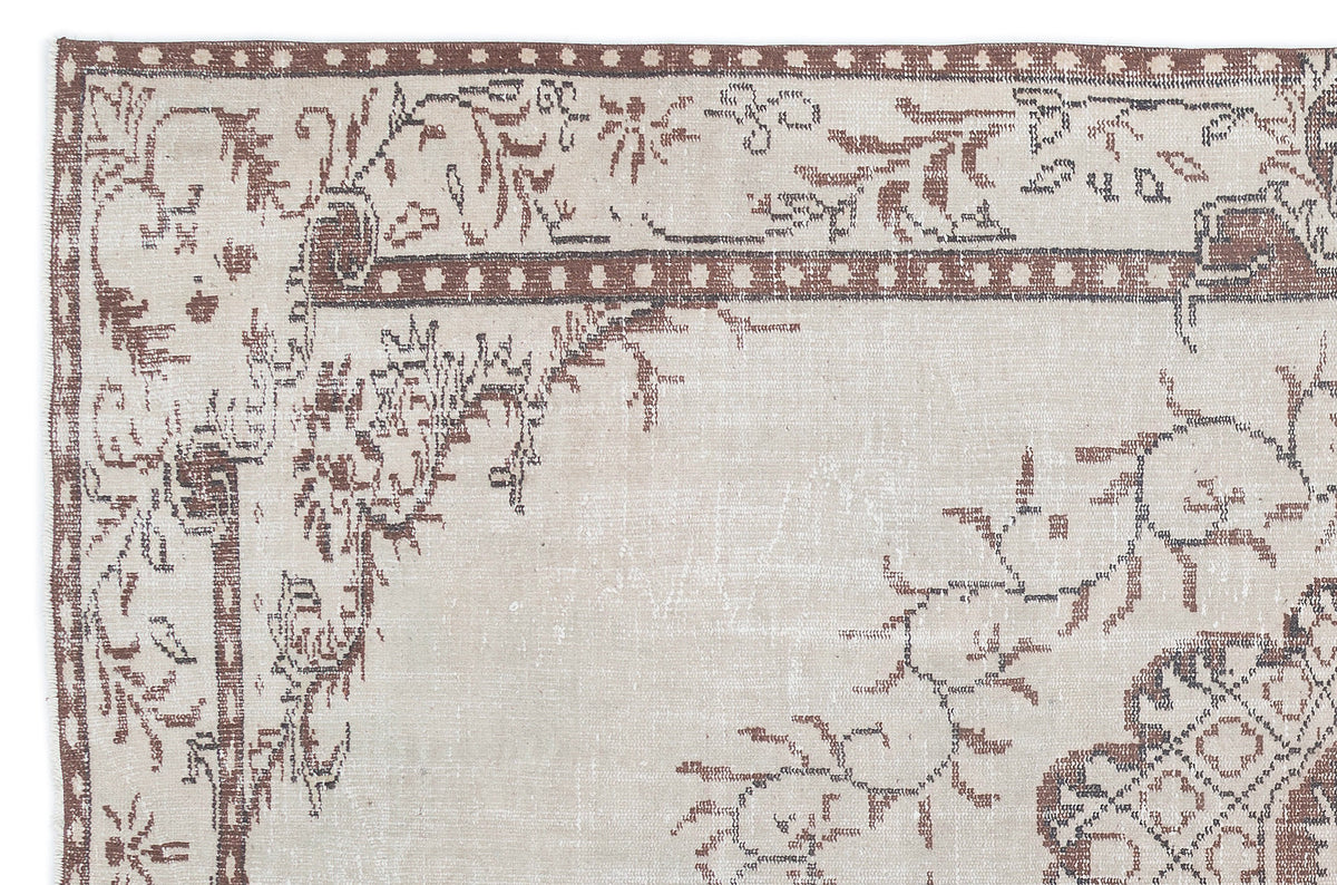 Beige and brown distressed rug with a traditional floral border and central medallion motif.