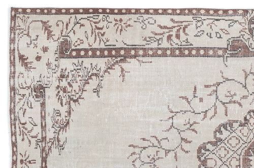 Load image 1 in gallery view. Beige and brown distressed rug with a traditional floral border and central medallion motif.