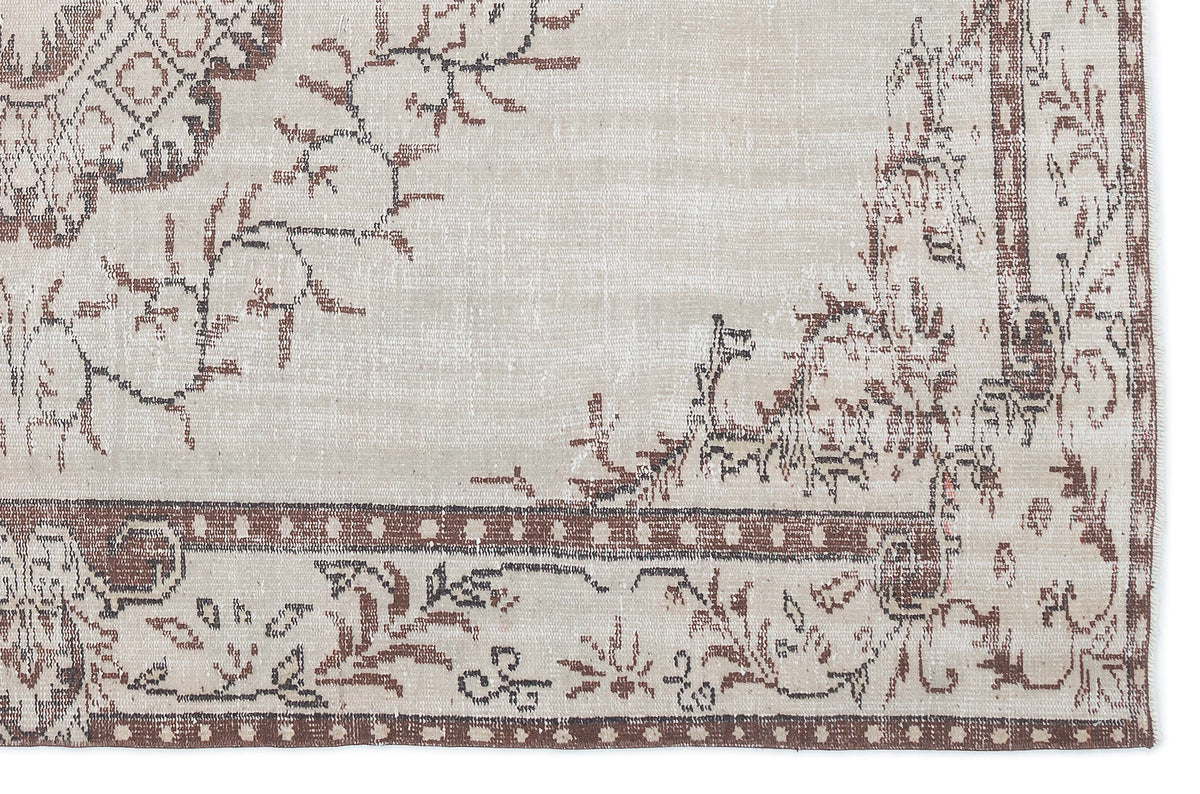 Beige and brown vintage-style rug with a distressed floral medallion pattern and a geometric border.
