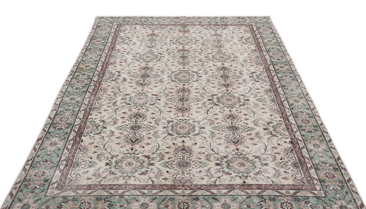 Cream, sage green, and mauve traditional rug with a distressed floral medallion pattern on a white background.
