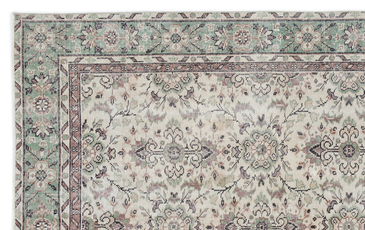 Cream, sage green, and brown traditional rug with a distressed floral medallion pattern and ornate border.