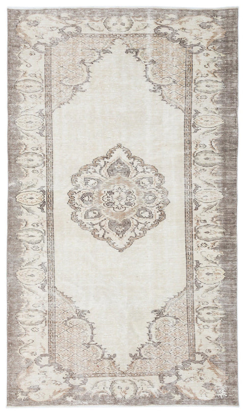 Load image 1 in gallery view. Cream and taupe distressed rug with a central floral medallion and ornate geometric border.