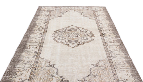 Load image 1 in gallery view. Beige and taupe distressed vintage-style rug with a central medallion and ornate border pattern on a white background.