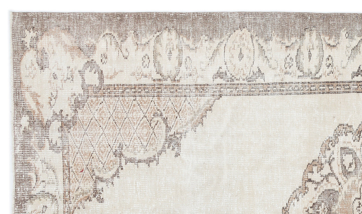 Distressed beige and taupe rug with a faded traditional medallion and geometric border pattern.