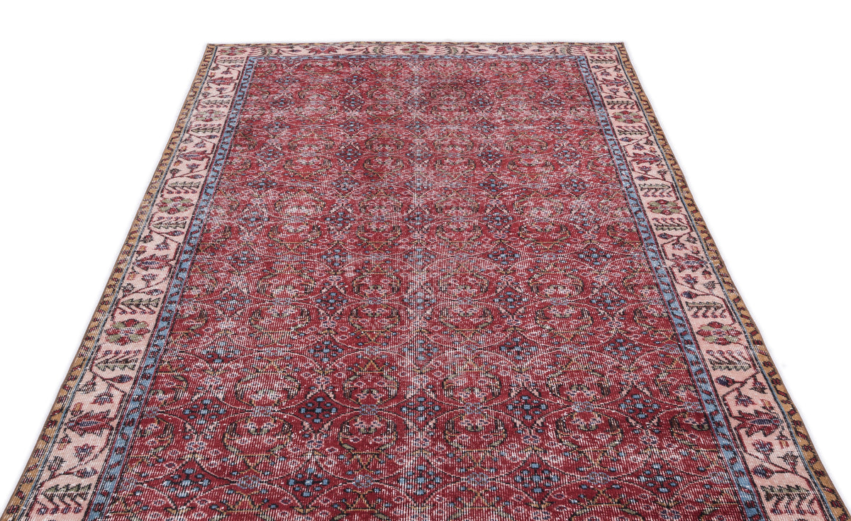 Distressed red Persian-style rug with a repeating floral medallion pattern and a multi-colored border on a white background.