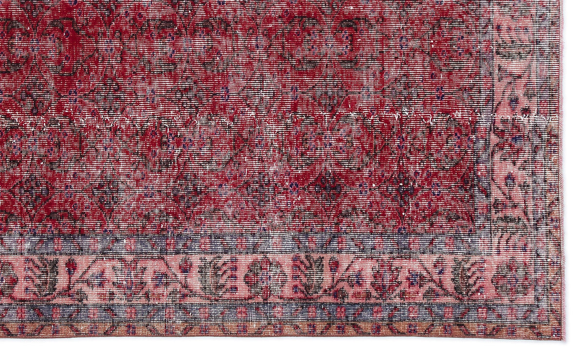 Distressed red and pink traditional rug with a dark floral medallion pattern and a detailed geometric border.