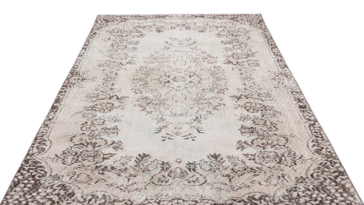Distressed beige and brown rug with a central floral medallion and ornate border pattern on a white background.