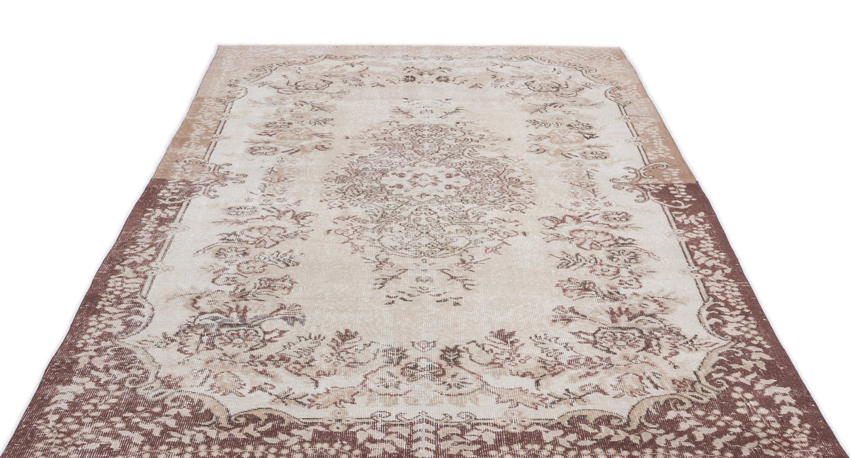 Beige and brown distressed area rug with a central floral medallion and ornate border on a white background.