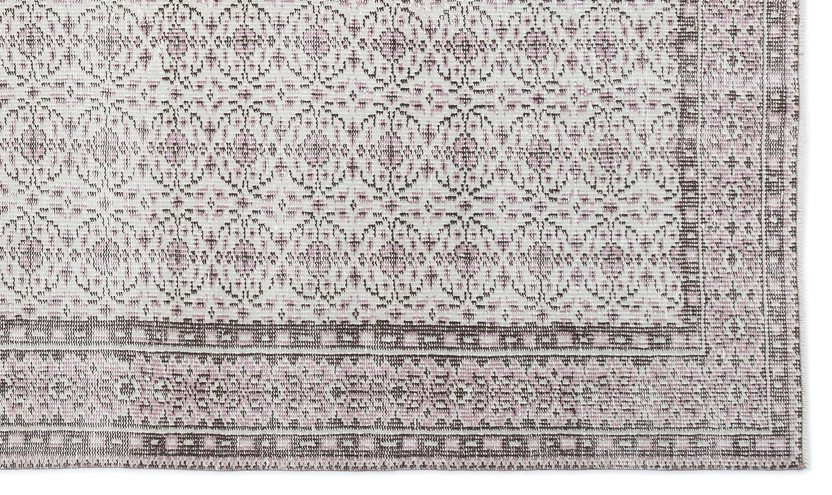 Off-white and dusty rose rug with a repeating geometric medallion pattern and a wide, detailed border.