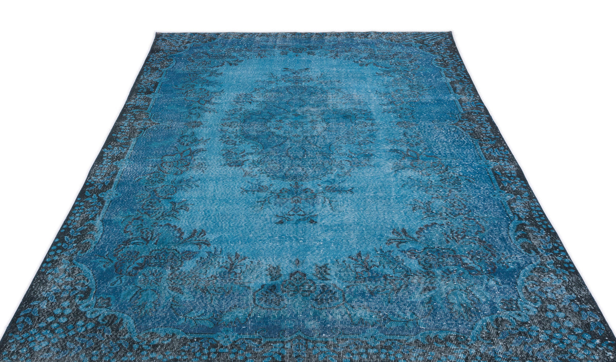 Bright blue distressed rug with a dark charcoal floral medallion and ornate border on a white background.