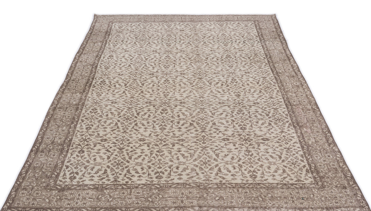 Taupe and cream area rug with a distressed traditional floral medallion pattern and a wide decorative border.