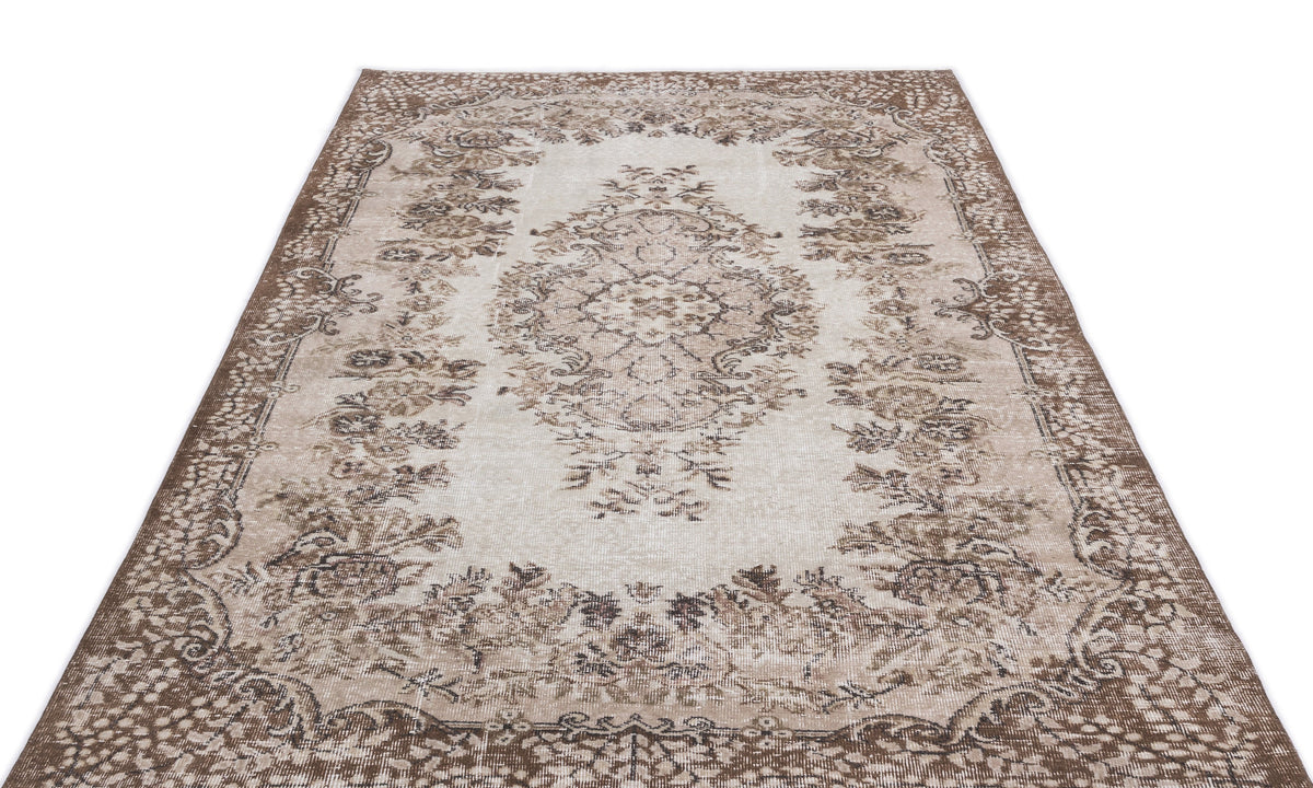 Beige and brown vintage-style rug with a central floral medallion and ornate border on a white background.