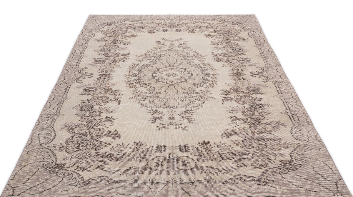 Beige and taupe distressed rug with a traditional floral medallion pattern and ornate border on a white background.
