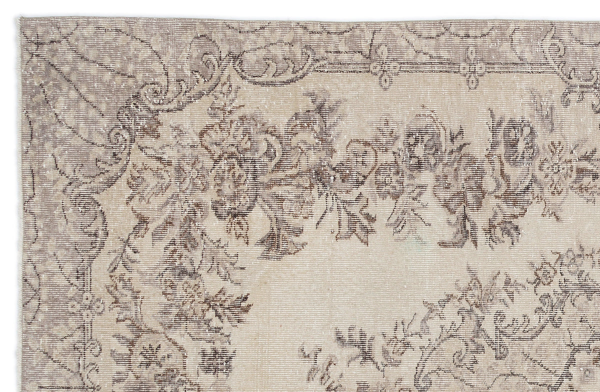 Beige and taupe distressed rug with a faded floral medallion pattern on a white background.