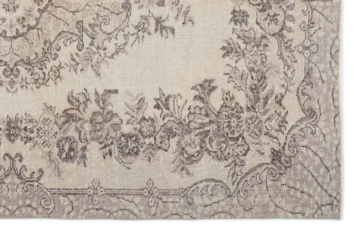 Beige and taupe distressed rug with a faded floral medallion pattern.