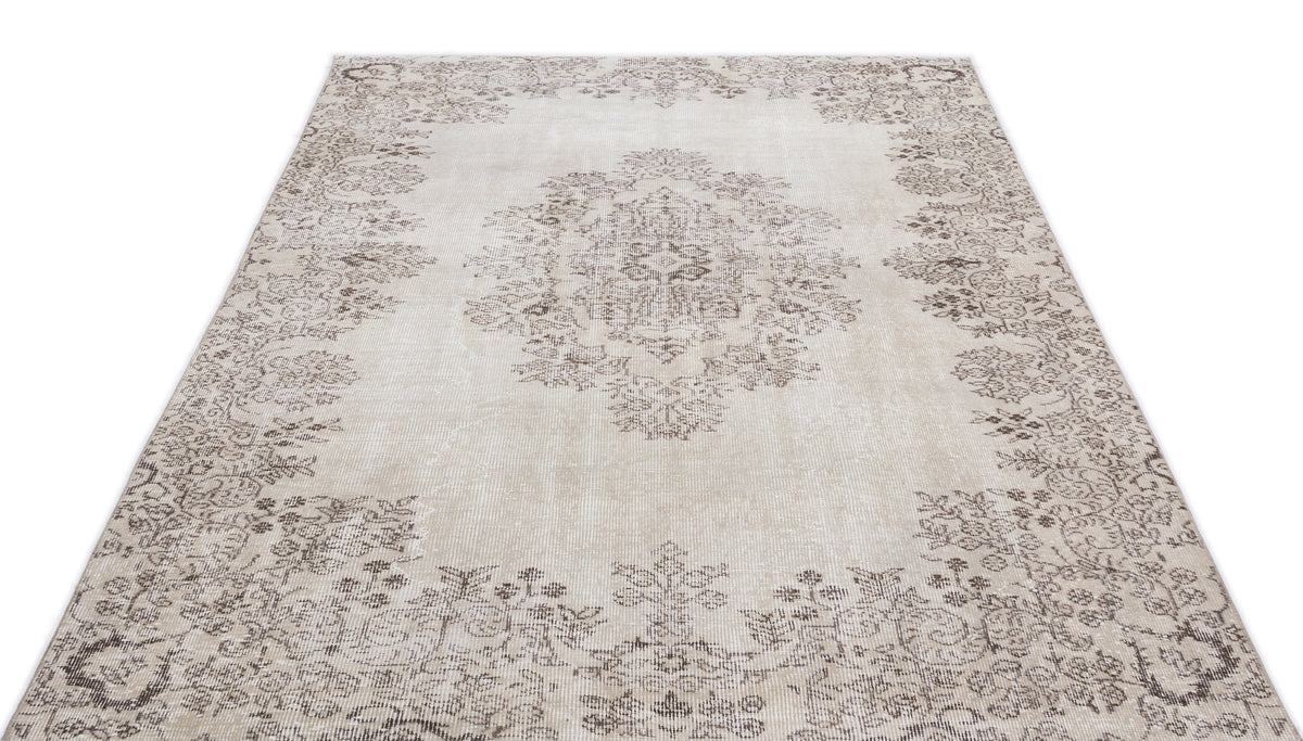 Beige and taupe distressed rug with a central floral medallion and ornate border pattern on a white background.